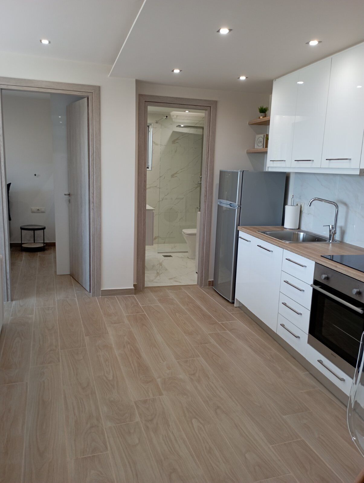Una cocina moderna con gabinetes blancos, un refrigerador de acero inoxidable y un horno empotrado.