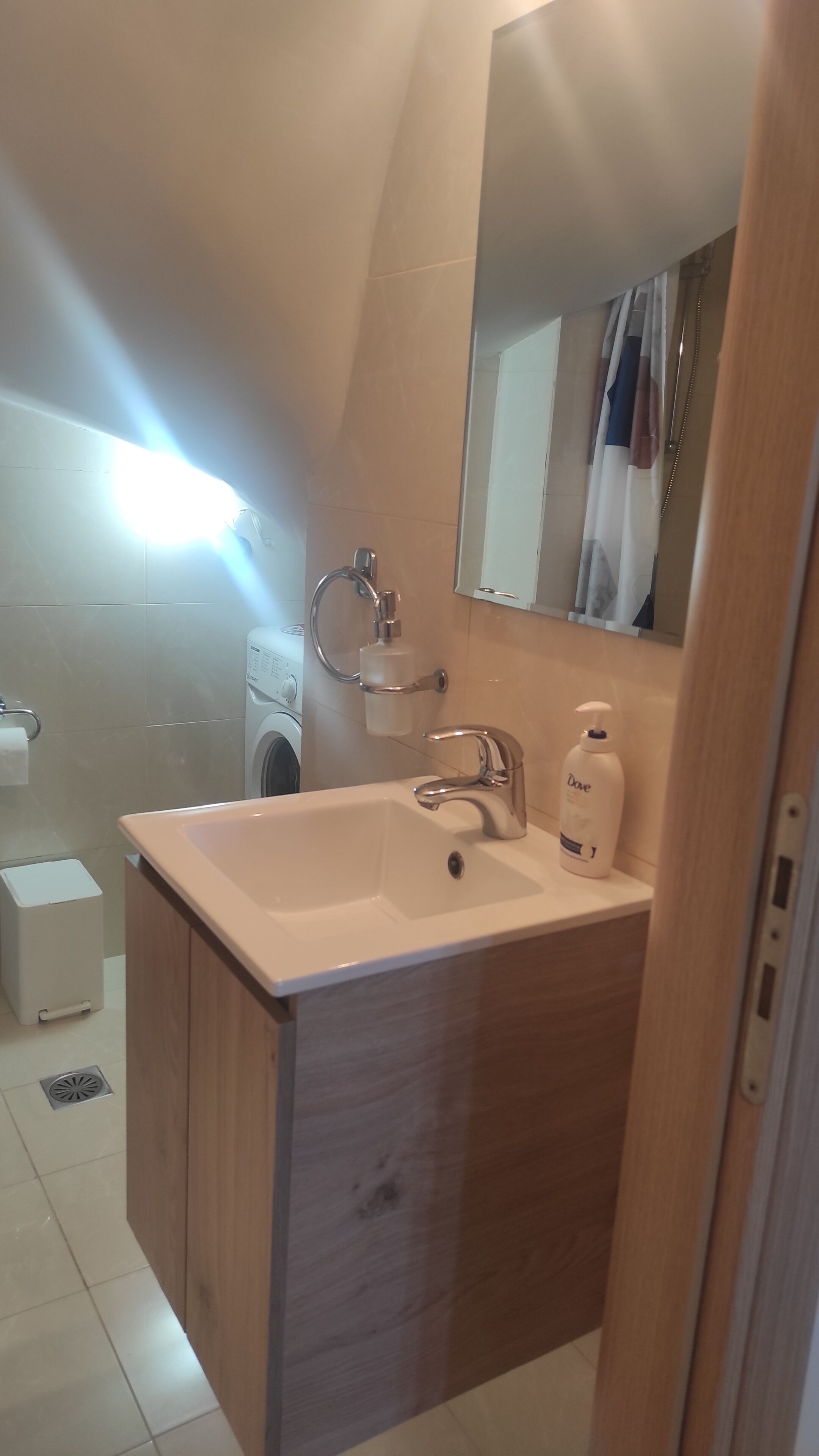A bathroom with a sink, mirror, and a washing machine.