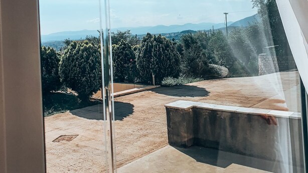 A view from a window with a clear sky, a patio area, and distant trees and hills. - Agriomata Vergas Apartments (Kalamata)