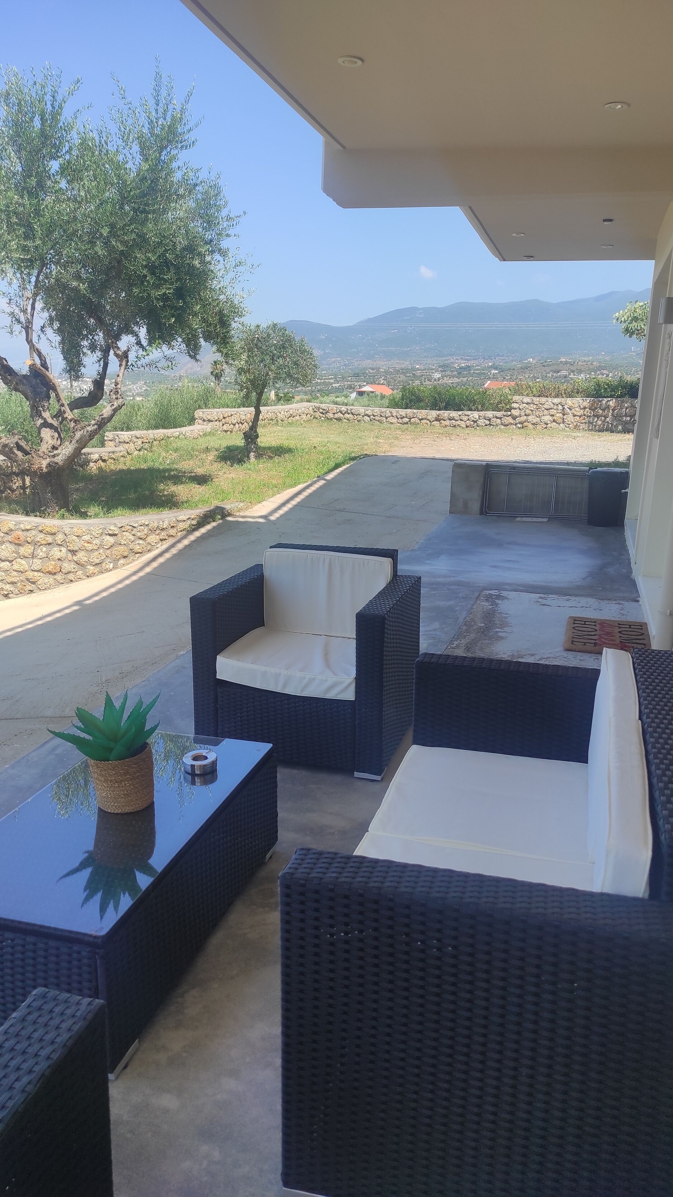 An outdoor seating area with wicker furniture and a view of the countryside.