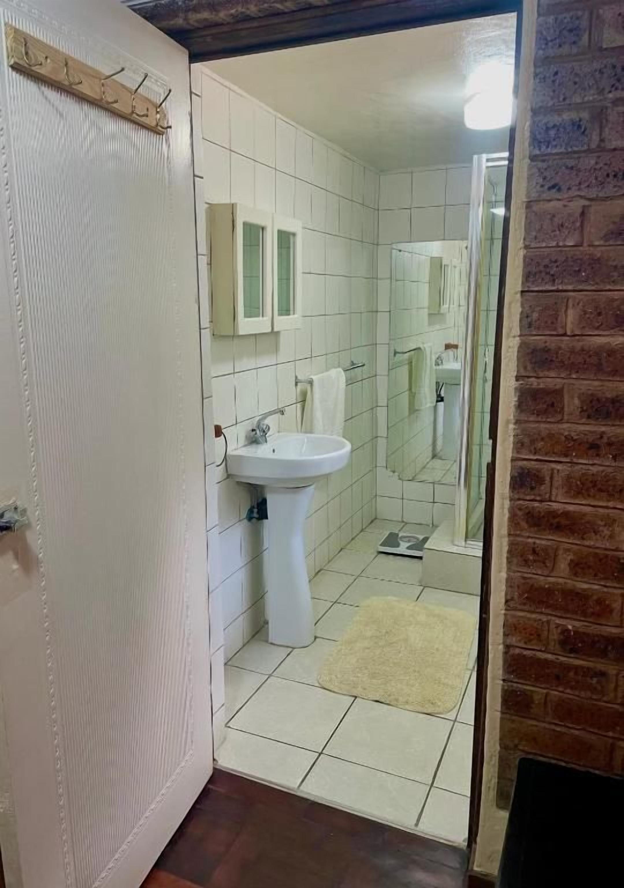 Un baño con lavamanos, espejo y suelo de baldosas.