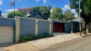 A residential house with a garage, a large wooden door, and a flag. - Timebridge Mansion (Johannesburg)
