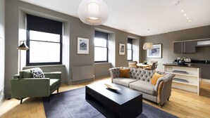A modern living room with a sofa, coffee table, and a dining area with a table and chairs. - JOIVY 5-star Luxurious George Street Apartment (Edinburgh)