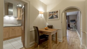 A dining area with a wooden table and chairs, a light fixture on the wall, and a painting above the table. - JOIVY New Town Boutique Apartment on India Street (Edinburgh)