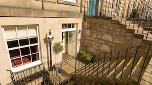 A multi-story building with a stone staircase, a metal railing, and a door with a blue handle. - JOIVY New Town Boutique Apartment on India Street (Edinburgh)