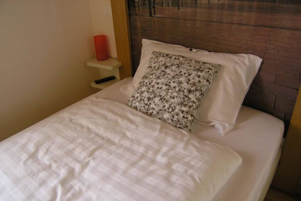 Un lit avec un coussin à motifs floraux et une couverture blanche.