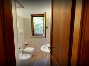 A bathroom with two toilets, a sink, and a window.