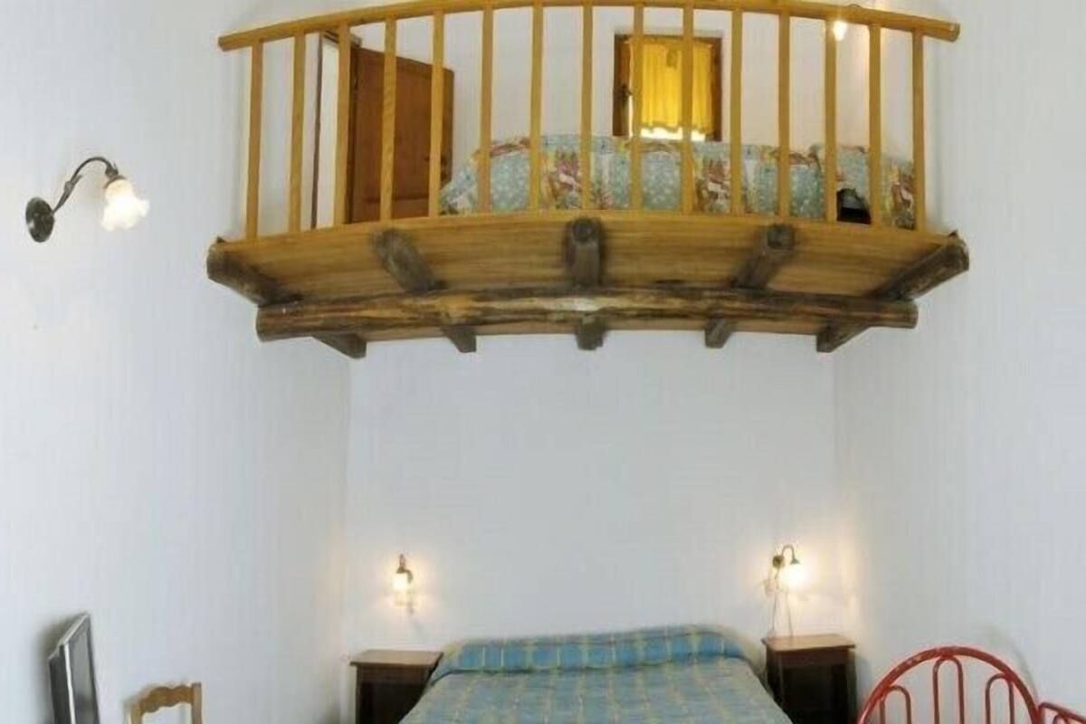 Un dormitorio con estructura de cama de madera, un balcón pequeño y dos lámparas fijadas a la pared.