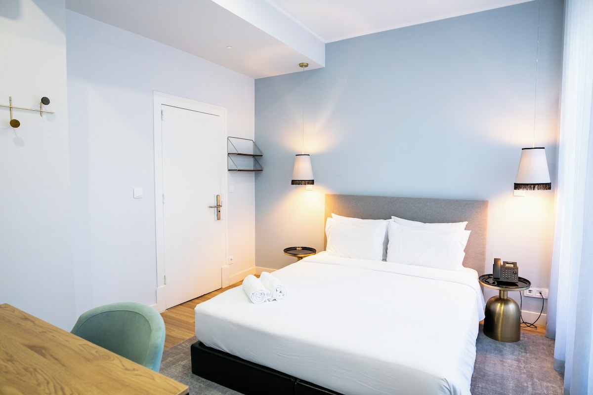 Une chambre d’hôtel avec un lit, des tables de chevet, un bureau et une chaise.