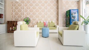 A modern living room with white sofas, a glass coffee table, and a decorative fan.