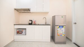 A compact kitchen with white cabinets, a stainless steel refrigerator, and a built-in oven.