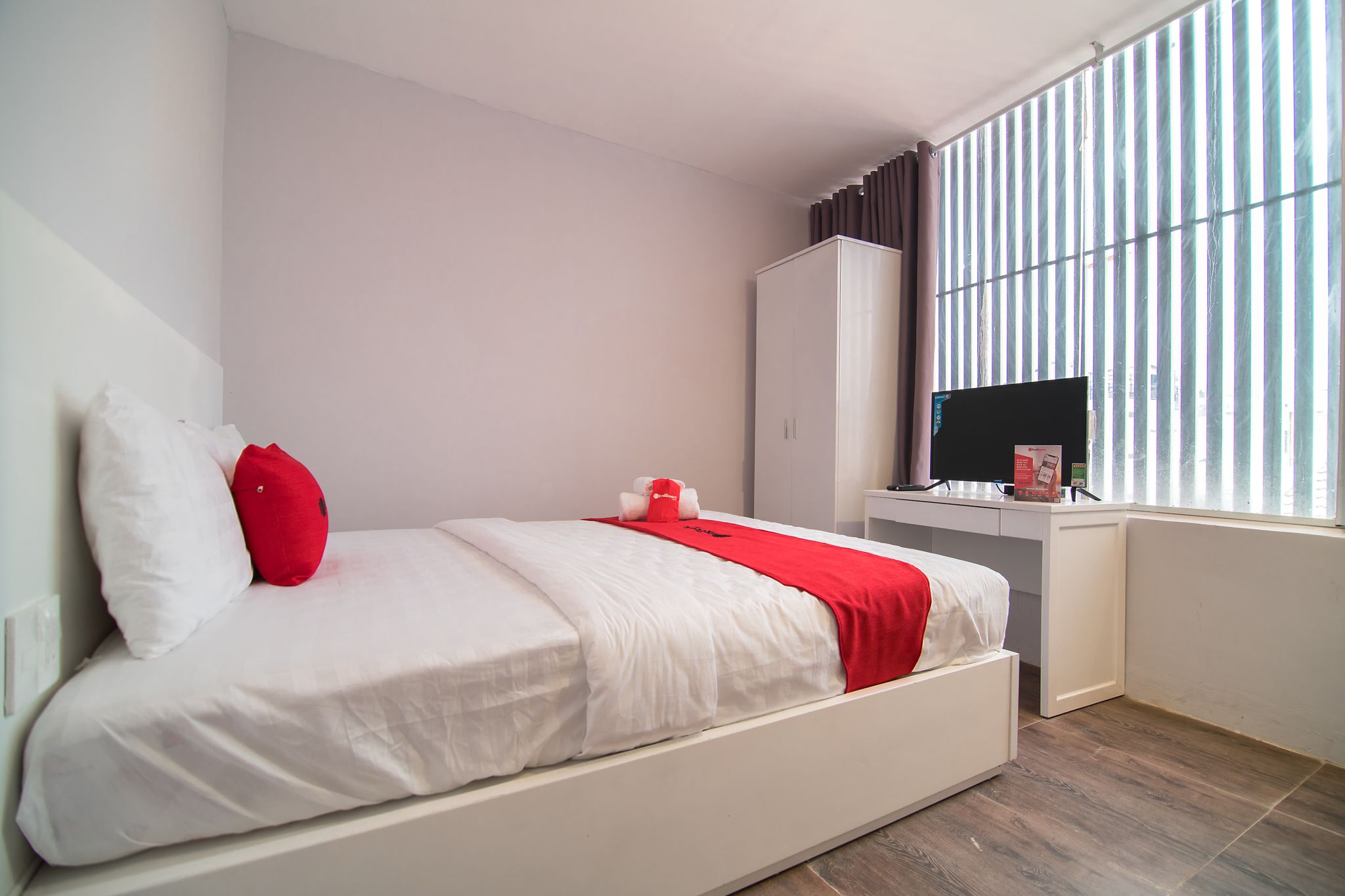 A modern bedroom with a bed, a desk, and a TV.