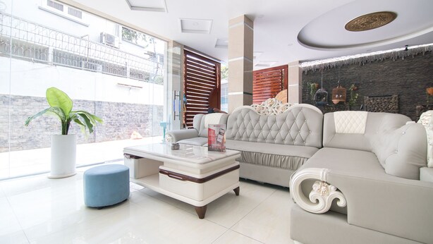 A modern living room with a large window, a sofa, a coffee table, and a potted plant.