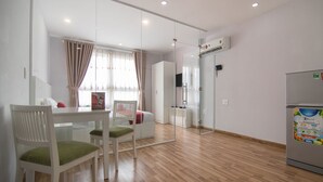 A modern kitchen with a refrigerator, a dining table with chairs, and a window with curtains.