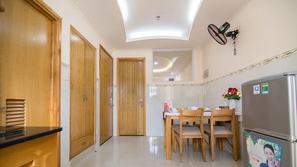 Une cuisine moderne avec des meubles en bois, une table à manger avec des chaises, un réfrigérateur et un ventilateur de plafond.
