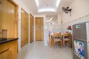 Eine moderne Küche mit Holzausbau, einem Esstisch mit Stühlen, einem Kühlschrank und einem Deckenventilator.