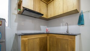 Une cuisine avec des meubles de rangement en bois, un plan de travail noir, un évier en acier inoxydable et une hotte aspirante.