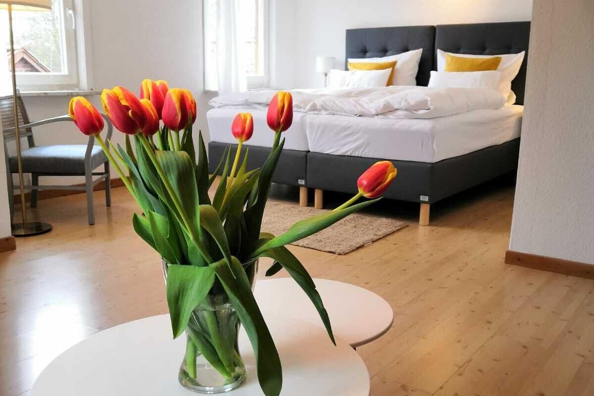 Een moderne slaapkamer met een bed, nachtkastje en een vaas tulpen.