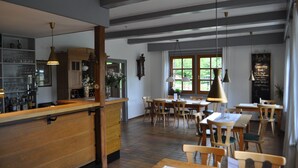 A restaurant with wooden furniture, pendant lighting, and a chalkboard menu.