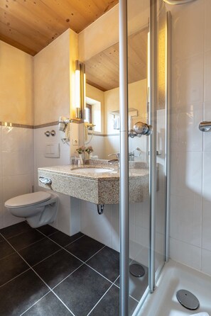 Une salle de bain moderne avec une douche à parois de verre, un lavabo en granit et des toilettes.