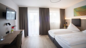 A hotel room with a bed, a desk, a TV, and curtains. - Hotel Alter Hof (Vaterstetten)