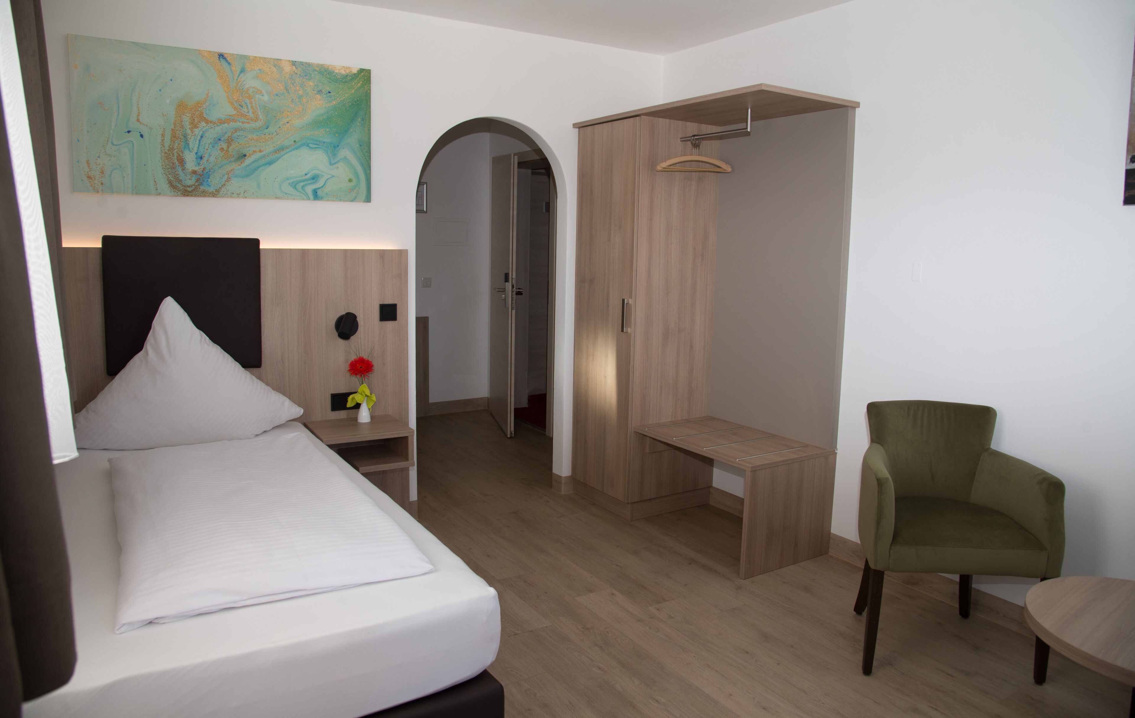 Een moderne hotelkamer met een bed, een bureau, een stoel en een kledingkast.