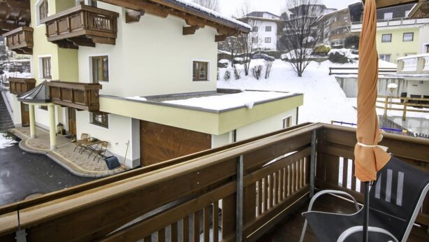 En balkon med trægelænder med udsigt over en sneklædt landsby.