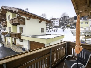 Ein Balkon mit Holzgeländer mit Blick auf ein schneebedecktes Dorf.