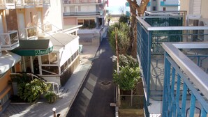 A hotel with a green awning, a covered outdoor seating area, and a street view. - App'artamento Soyus n.10 (Jesolo)
