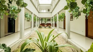 A spacious atrium with a high ceiling, large windows, and hanging plants. - OYO 882 Puri Gevana Guest House (Padang Panjang)