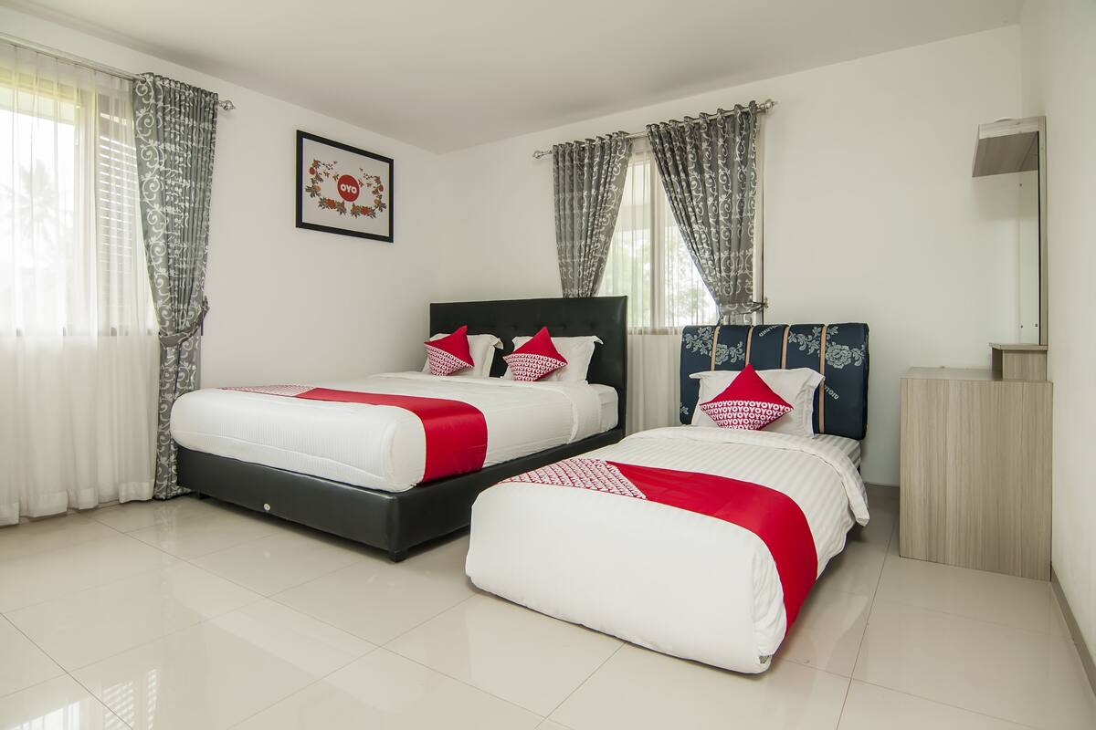 A hotel room with two beds, a wooden nightstand, a mirror, and a framed picture on the wall.
