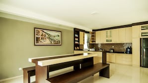 A modern kitchen with a central island, built-in cabinets, and a large window. - OYO 882 Puri Gevana Guest House (Padang Panjang)