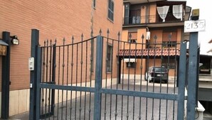 A gated entrance to a building with a brick facade and a balcony with a tiled roof. - Bed and breakfast Style (Rome)