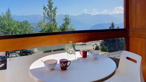 Un balcón con mesa, sillas y vistas a las montañas.