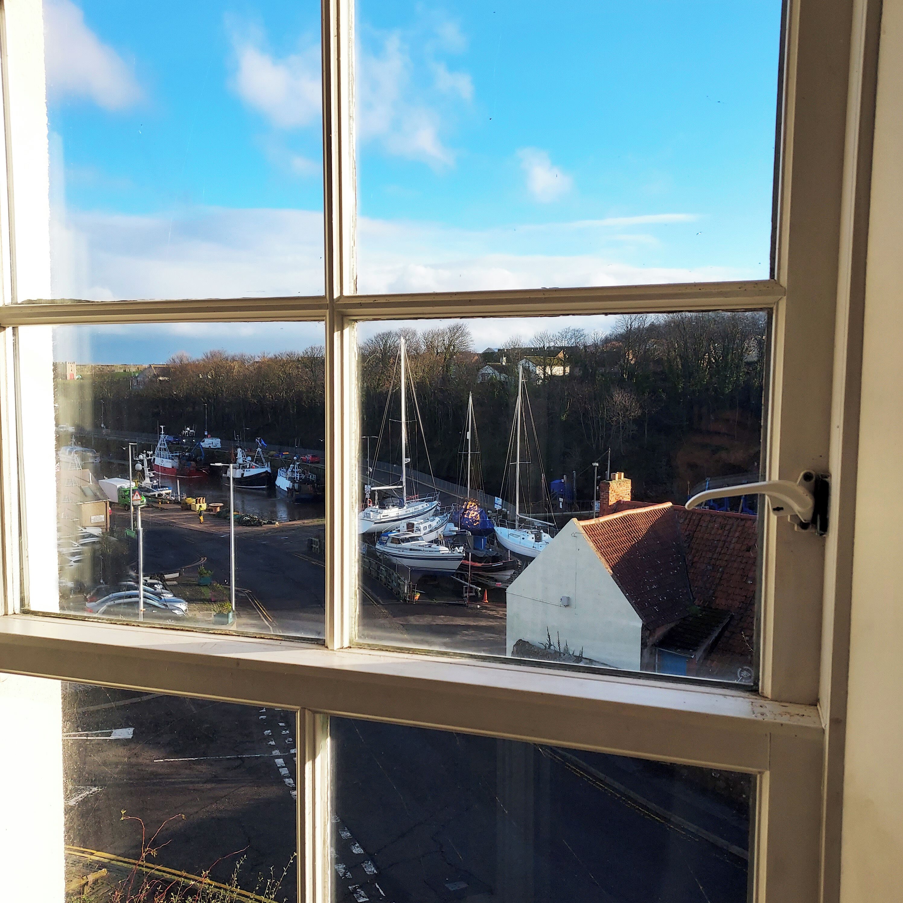 A view through a window with a clear sky and a marina with boats docked.