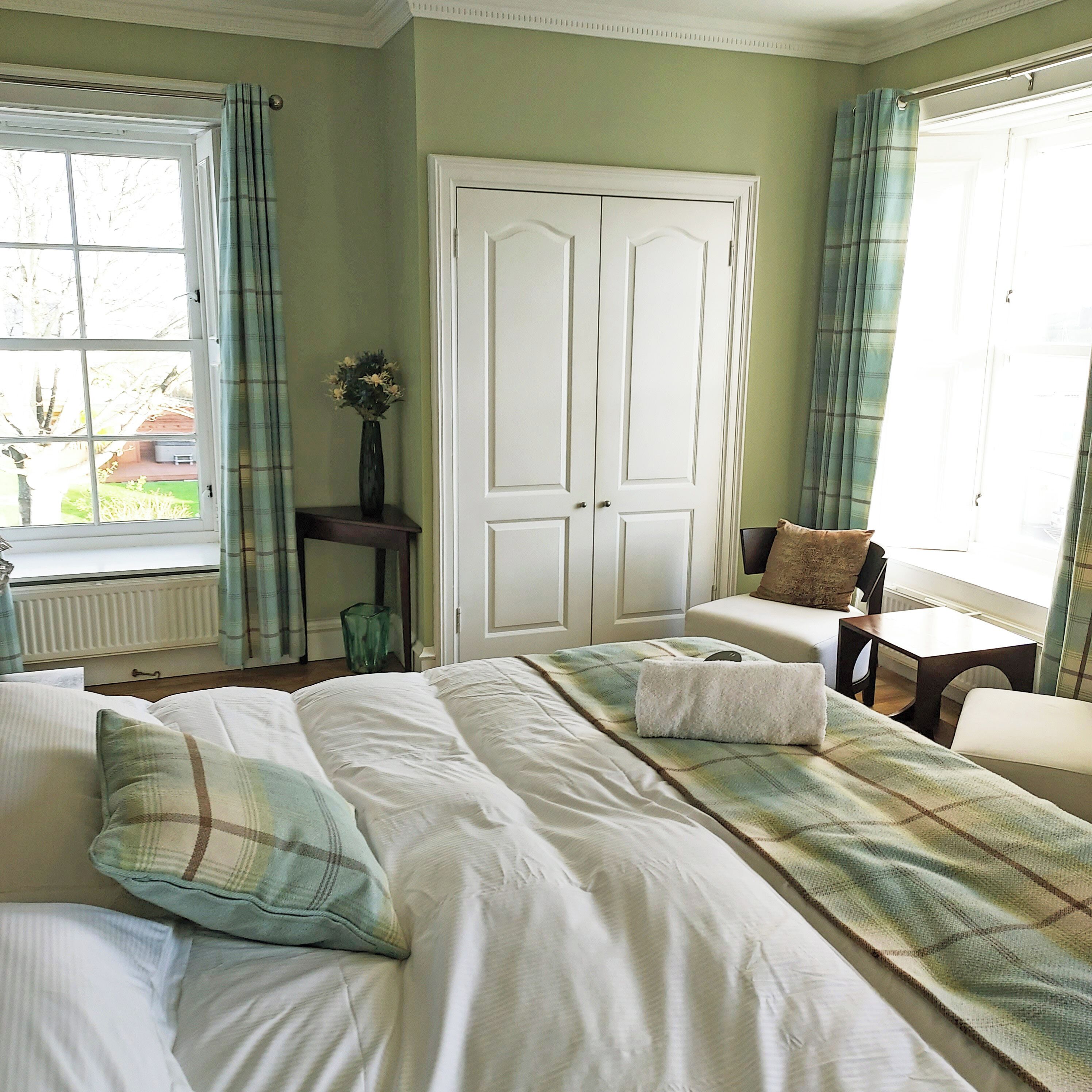 A bedroom with a bed, a chair, a table, a window, and a door.