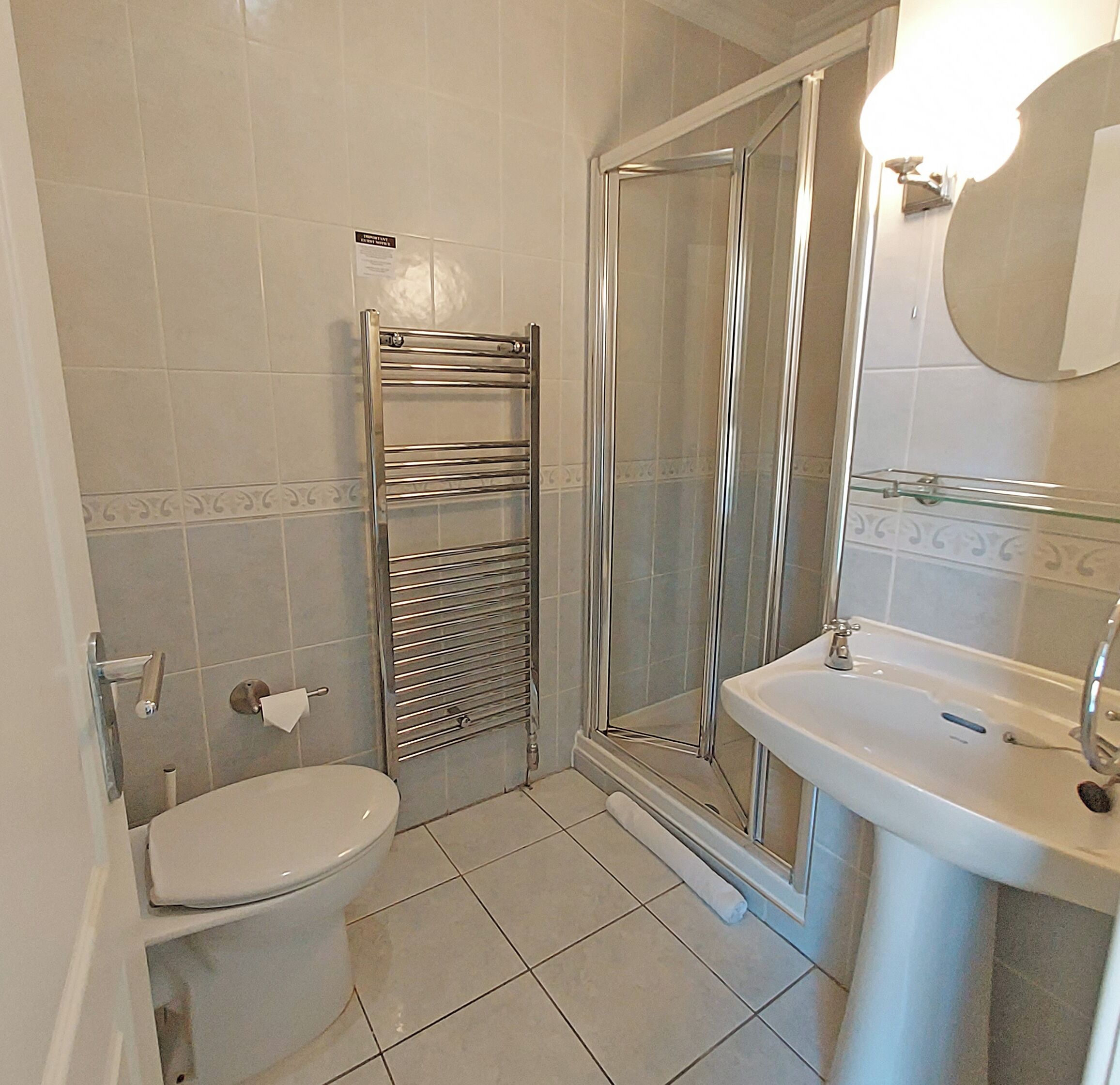 A bathroom with a toilet, a glass shower enclosure, and a sink with a mirror.