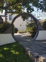 Un arco de piedra que da acceso a un camino, con un edificio al fondo.