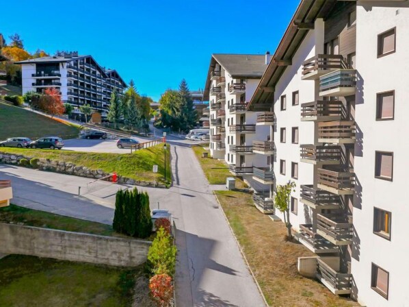 Ein Wohngebiet mit modernen Mehrstöckhäusern, einem Parkplatz und blauem Himmel.