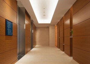 A corridor with wooden panel walls, a ceiling with recessed lighting, and a floor with a light-colored tile. - Hotel Kaze no Umi (Shimonoseki)