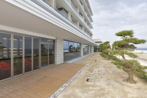 A modern hotel with a long, covered walkway, outdoor seating, and a view of the ocean. - Hotel Kaze no Umi (Shimonoseki)