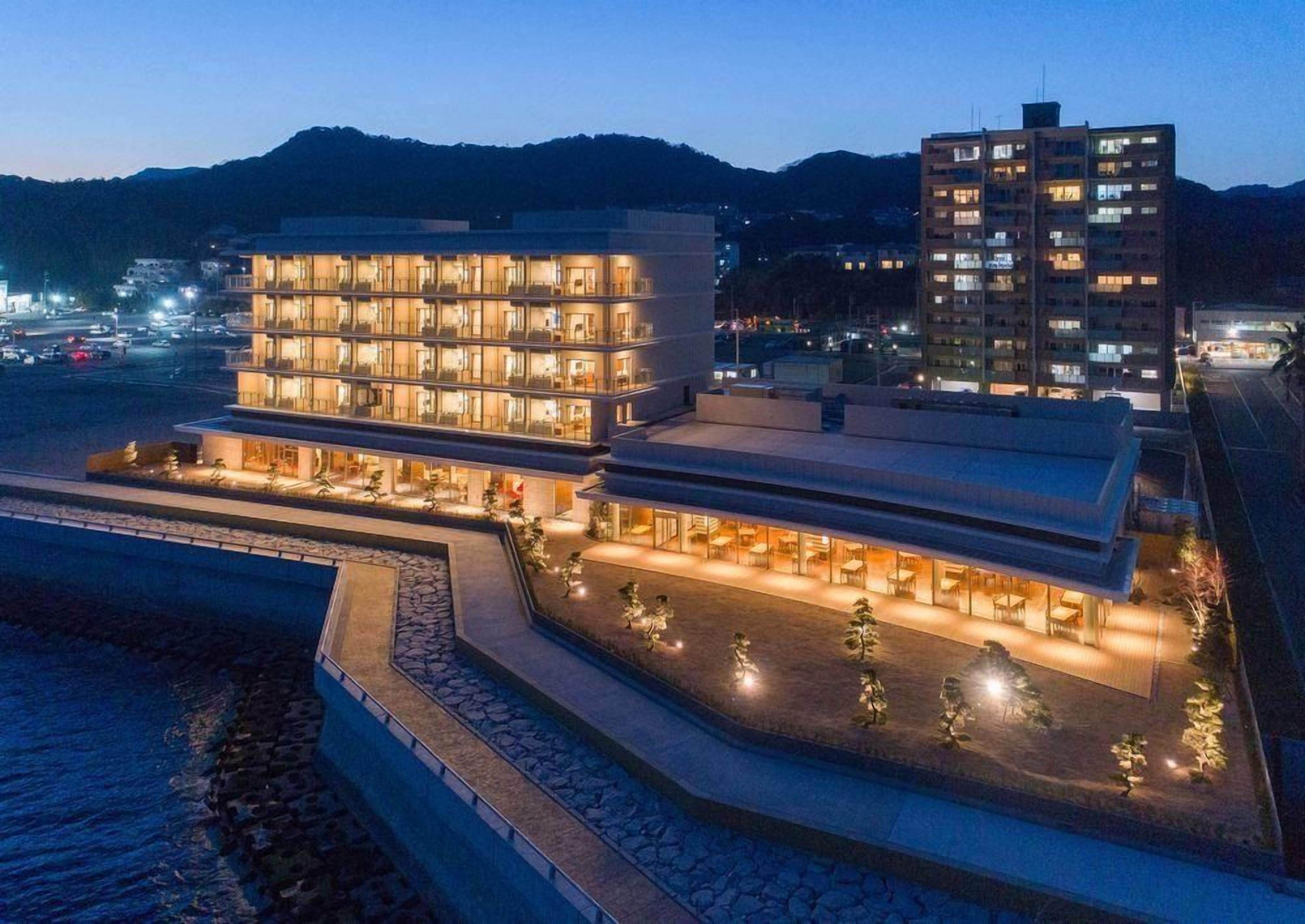 Un hôtel à plusieurs étages doté d’une piscine et d’un espace extérieur aménagé avec des sièges.