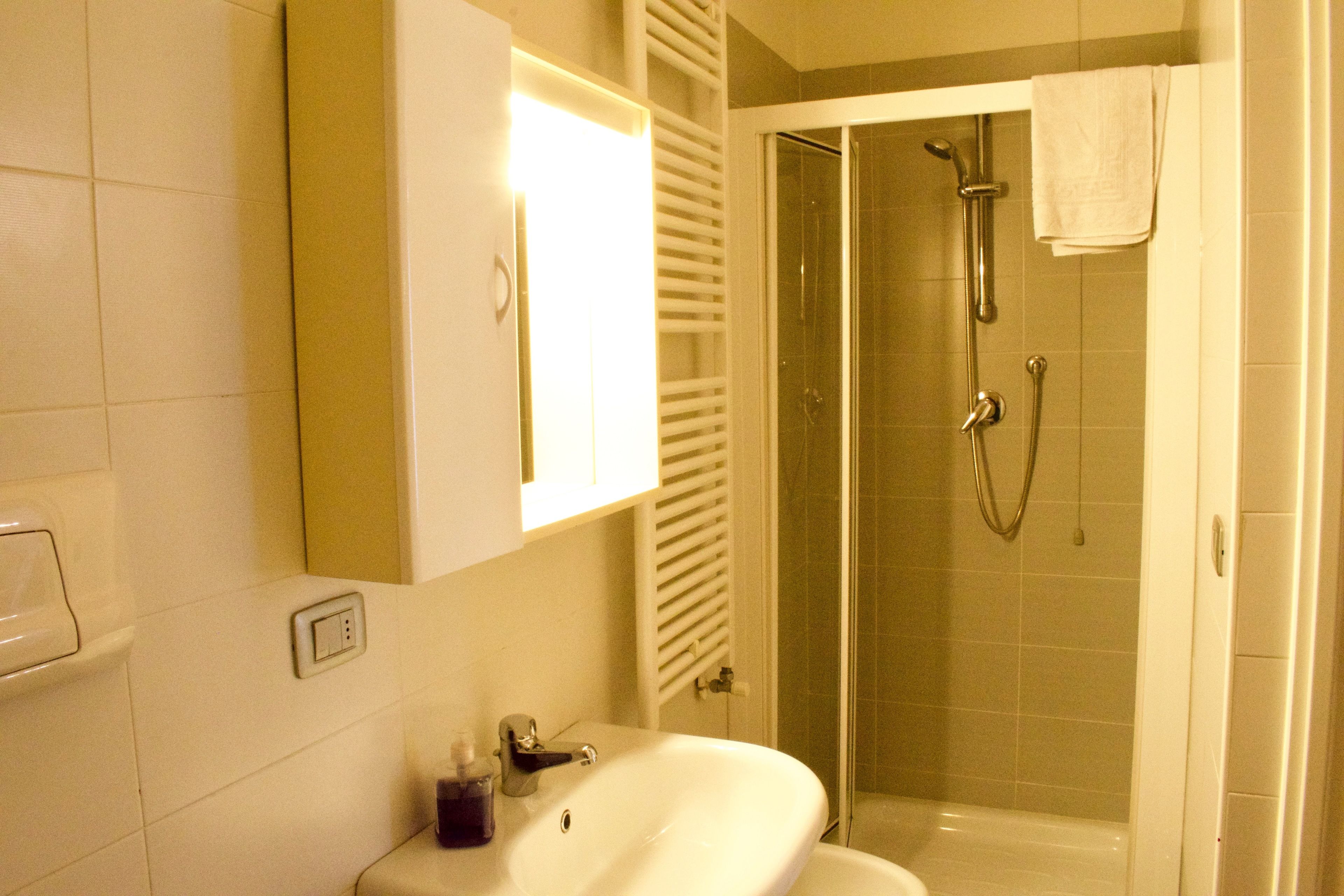 Ein Badezimmer mit Waschbecken, Spiegel, Handtuchhalter und einer Duschkabine.