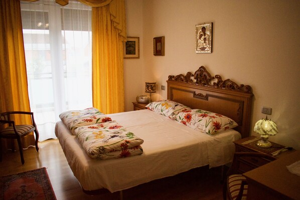 A bedroom with a wooden bed, a nightstand, a chair, a desk, and a lamp. - Appartamento Ca' Silis n. 7 (Jesolo)