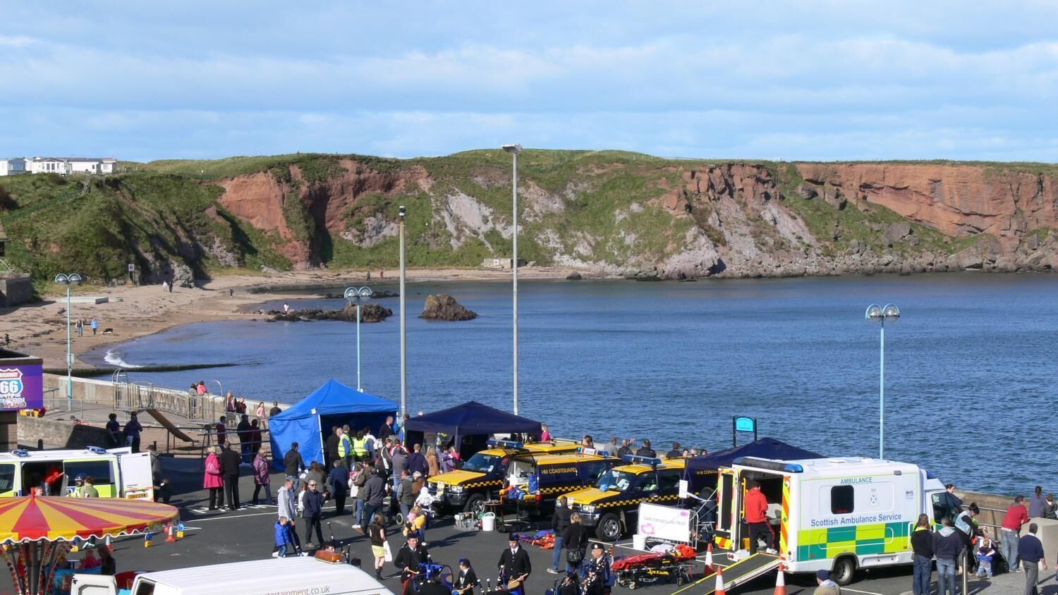 A coastal area with a beach, cliffs, and a Scottish Ambulance Service vehicle.
