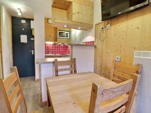A compact kitchen with wooden cabinets, a microwave, and a red tiled backsplash.