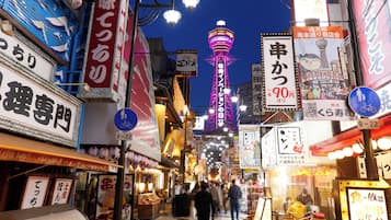A busy street with illuminated signs and a prominent tower in the background.