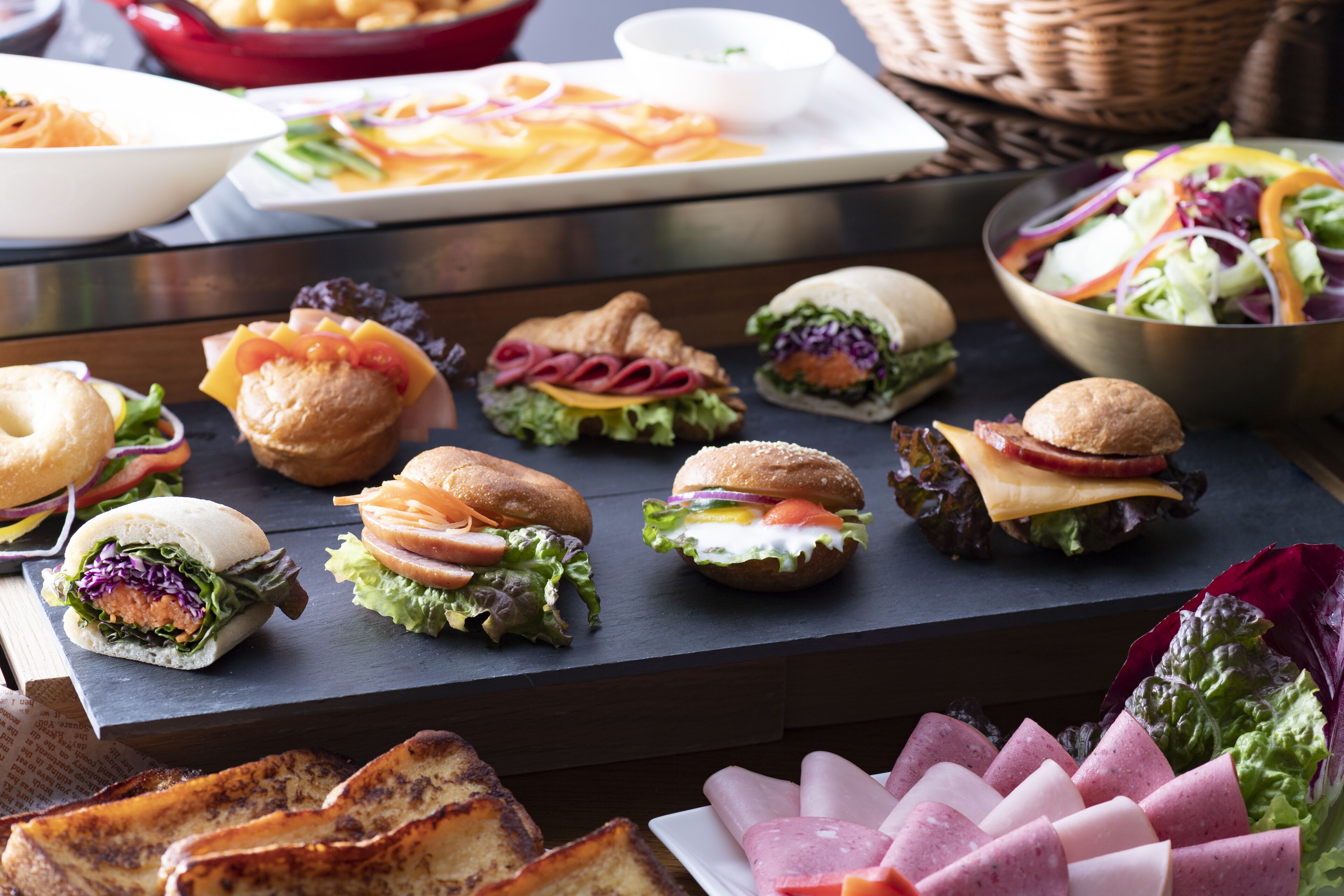 A variety of sandwiches and salads on a table.