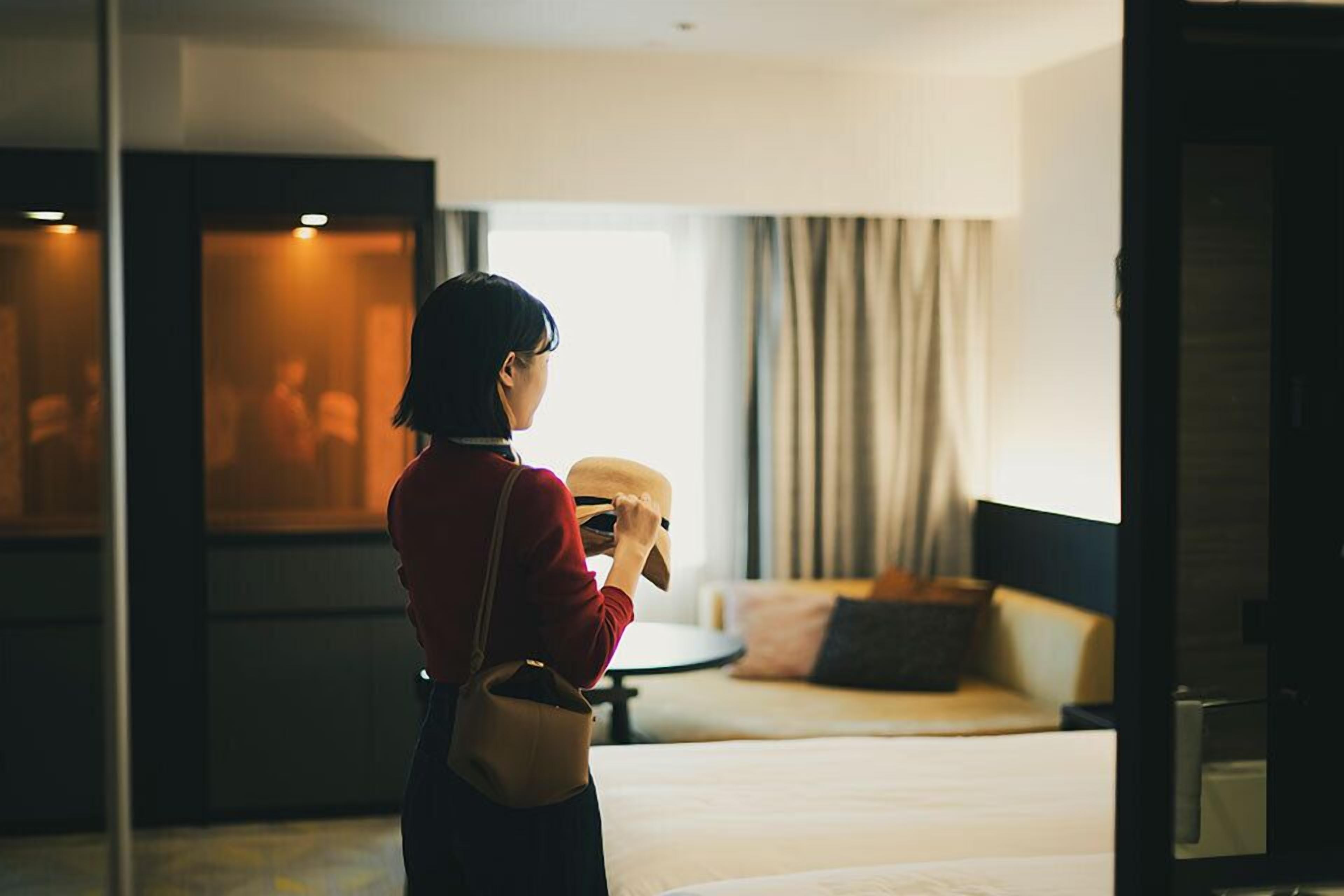 Una habitación de hotel con cama, sofá, ventana con cortinas y espejo.