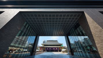 A modern building with a large glass entrance and a traditional structure in the background.